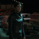 Maya standing in a used car lot.